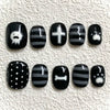 A set of press-on nails featuring various black and white designs including a ghost, cross, and bone.