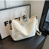 A cream corduroy multi-pocket tote bag with light vertical ribbing is displayed on a dark surface.