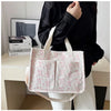 A white canvas tote bag with a pink strawberry pattern is held by a person against a light background.