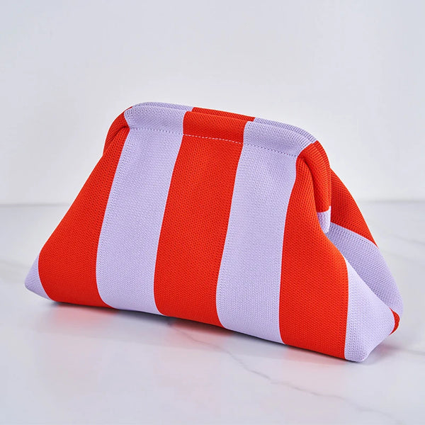 An orange and white woven striped crochet clutch bag lying on a white surface.