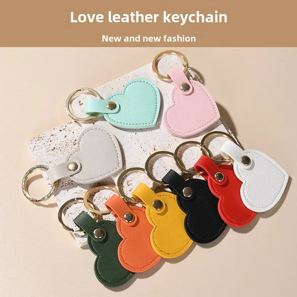 A collection of new and fashionable leather heart keychains in various pastel colors like mint green, pink, white, black, and