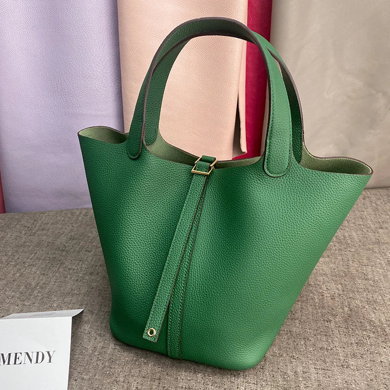 A dark green classic genuine leather bucket bag with a canvas strap is displayed on a neutral surface.