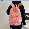 A pink nylon backpack with a cute bow print is worn by a person against a white background.