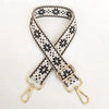 A beige and black patterned nylon crossbody bag strap with gold hardware.