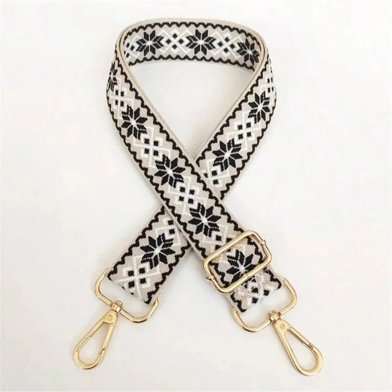 A beige and black patterned nylon crossbody bag strap with gold hardware.