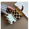 A hand holds a checkered PU leather mini card wallet with various cards and a leather card holder against a light brown backg
