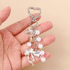 Silver pearl bow heart keychain hanging from a split ring on a hand