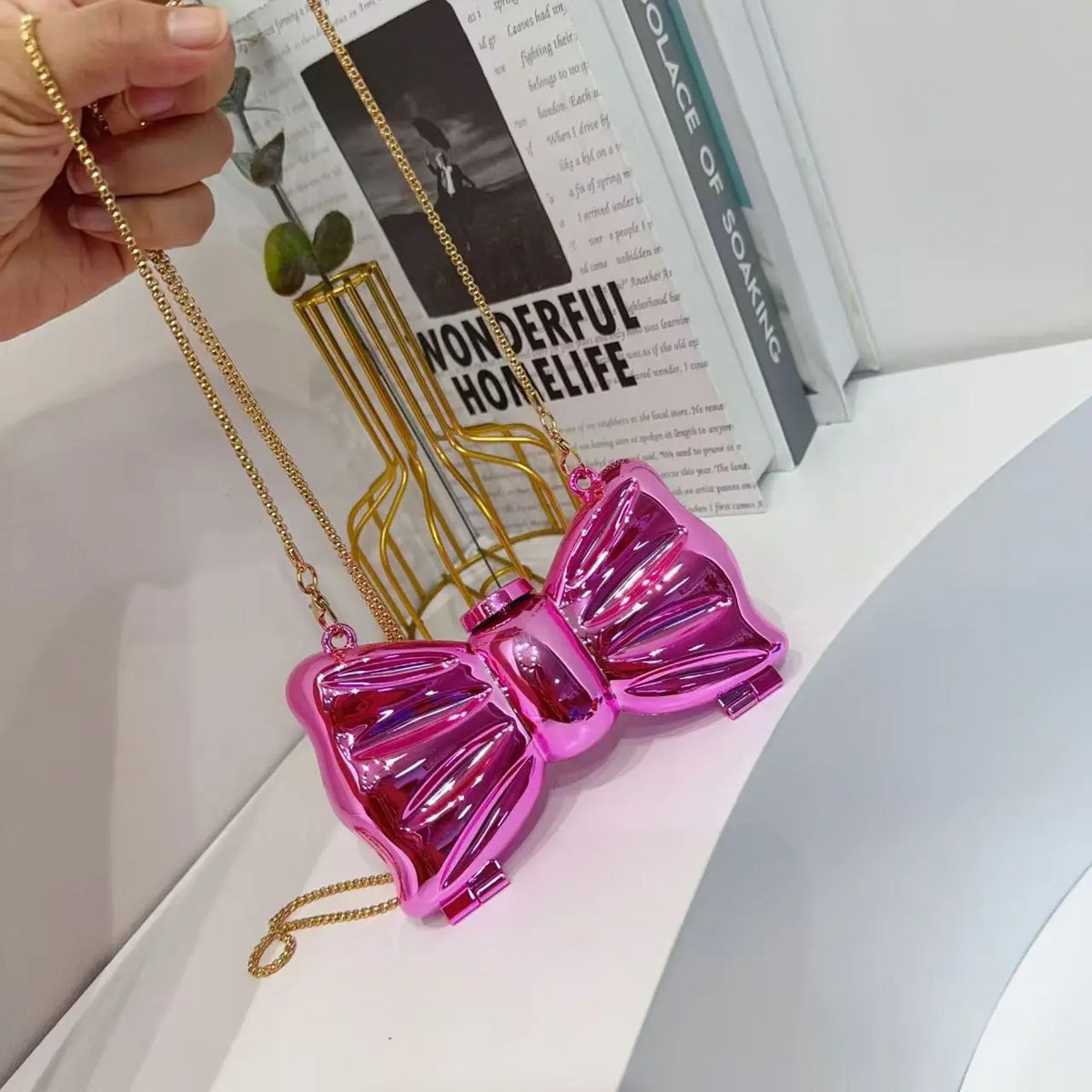 A glossy pink heart-shaped acrylic evening clutch with a gold chain strap displayed against a white background.