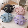 Flat lay of four instant-open makeup organizer bags in black, pink, light blue, and purple on a white table.