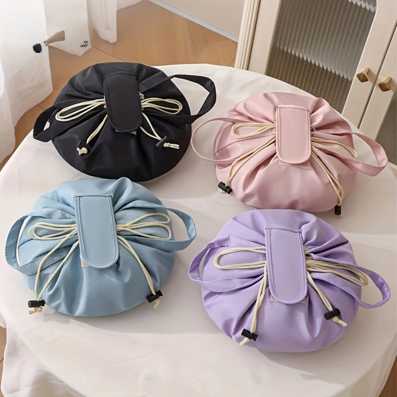 Flat lay of four instant-open makeup organizer bags in black, pink, light blue, and purple on a white table.