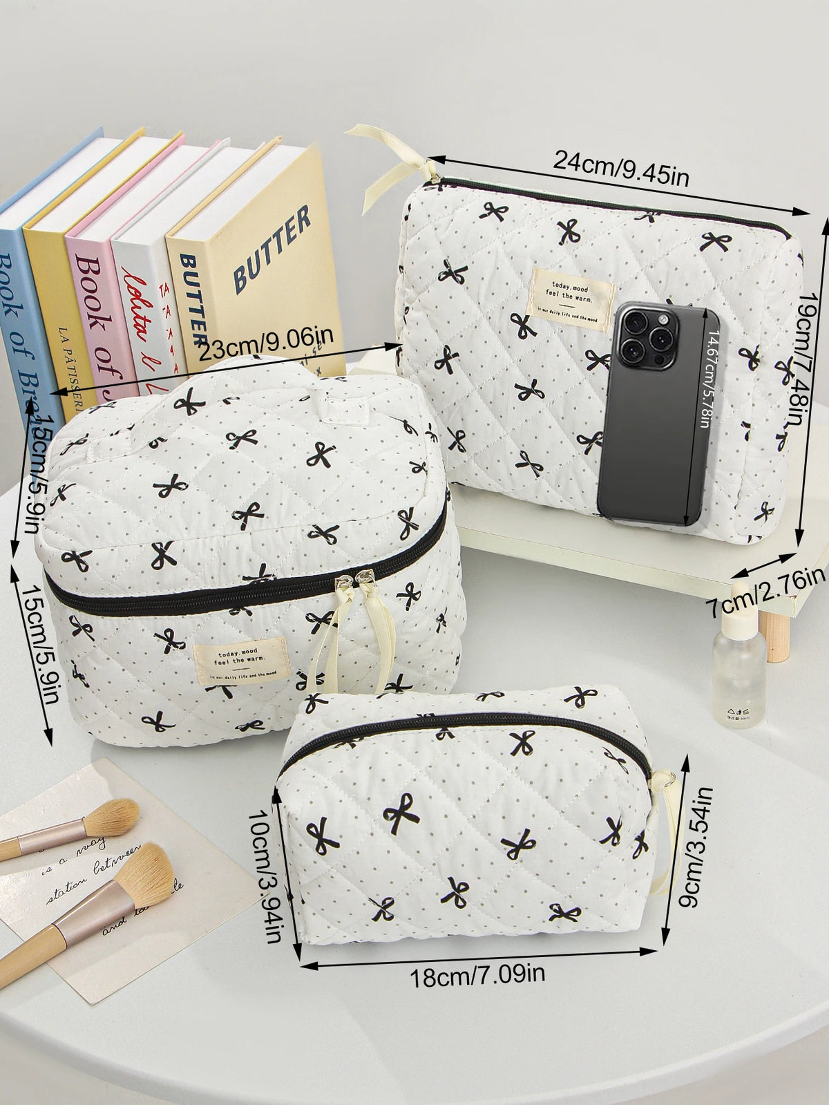 A white quilted makeup bag with black trim and a gold drawstring is shown next to various cosmetic brushes.