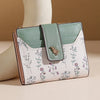 A light mint green and white patterned slim card holder wallet with a leather strap.