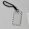 A white card holder with a rectangular frame and black polka dots is attached to a black lanyard.