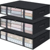 Three black under bed storage organizer bins filled with folded light-colored fabric and linen.