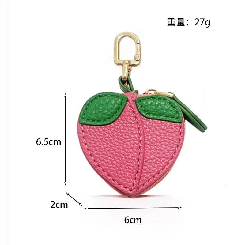 A pink and green fruit-shaped PU leather coin purse keychain with a gold-colored ring.