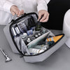 A hand is opening a gray portable waterproof travel toiletry bag filled with various grooming products.