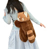 A person is holding a brown red panda plush toy with a light blue shirt and a white skirt.