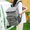 A person is carrying a gray insulated lunch backpack with a waterproof Oxford shell outdoors.
