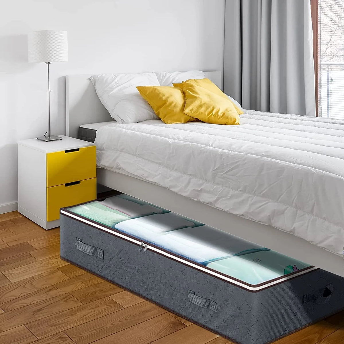 A bed with a storage organizer bin under the bed, featuring white bedding and yellow accents.