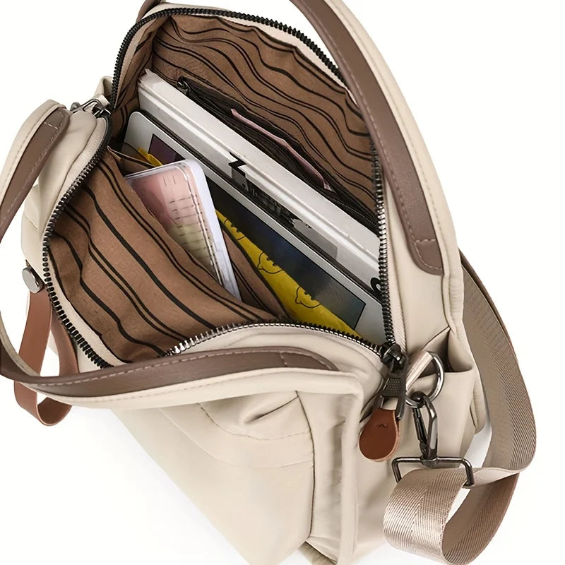 A beige shoulder crossbody bag with a zippered compartment showing a credit card and other items.