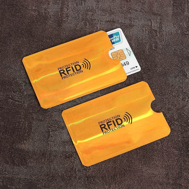 Two yellow anti-scan card sleeves for credit and RFID protection are shown on a dark surface.