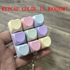 Une main tient une pile de keycaps pour clavier fidget en forme de macarons colorés.