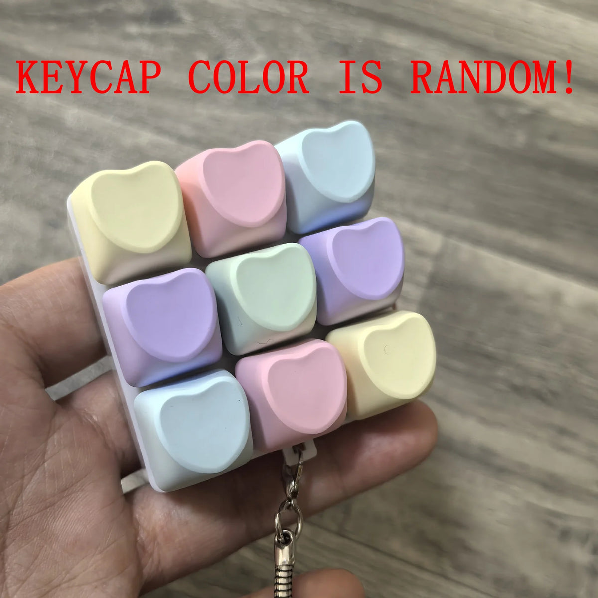 Une main tient une pile de keycaps pour clavier fidget en forme de macarons colorés.