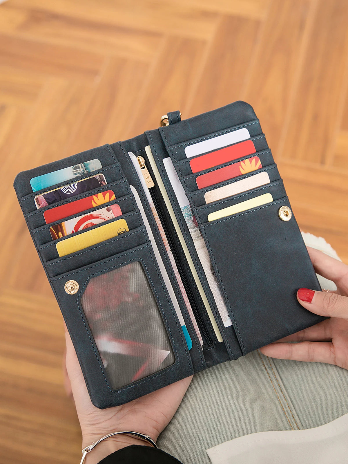 A dark gray retro long wallet with a double zipper and multiple card slots is held in a hand.