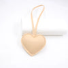 A light tan PU leather heart-shaped keychain with a loop for attachment.