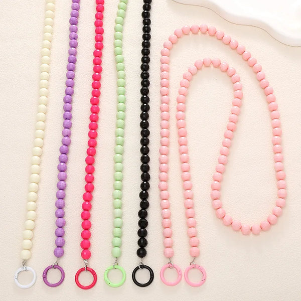 A collection of handmade acrylic bead cross phone charms in various colors including white, purple, pink, green, and black.