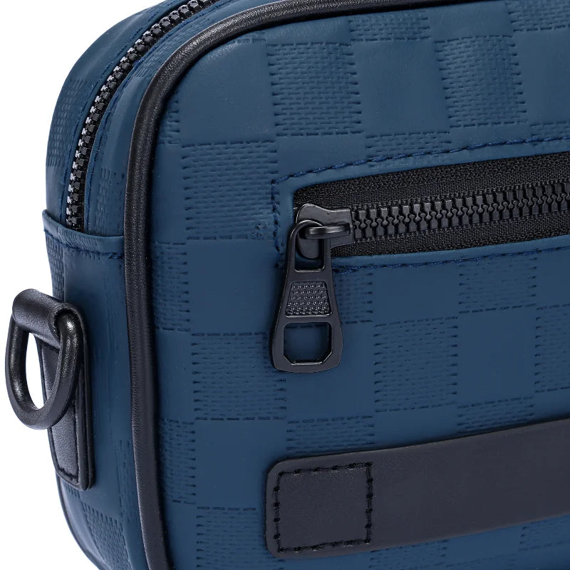 A close-up view of a navy blue PU leather crossbody bag with a zipper and adjustable strap.