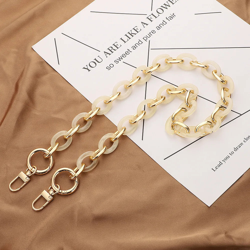 حامل سلسلة أكريليك بلون ذهبي معروض على ورقة أمام نسيج بني.