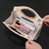 A light beige evening handbag with gold accents and a textured finish, shown open displaying makeup and accessories.