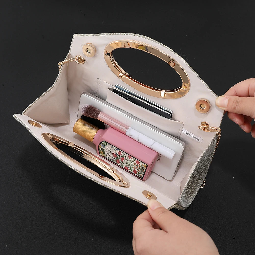 A light beige evening handbag with gold accents and a textured finish, shown open displaying makeup and accessories.