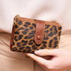 A brown leopard print women's wallet is held against a beige jacket.