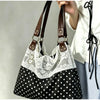 A close-up of a black and white polka dot patchwork shoulder bag with white lace trim being held by a hand.