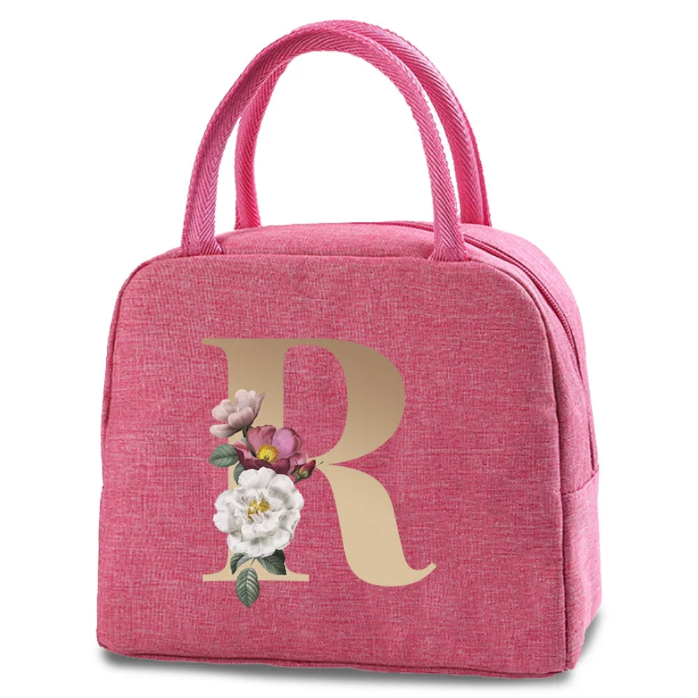 A pink insulated canvas lunch bag featuring a large gold letter R with floral accents.