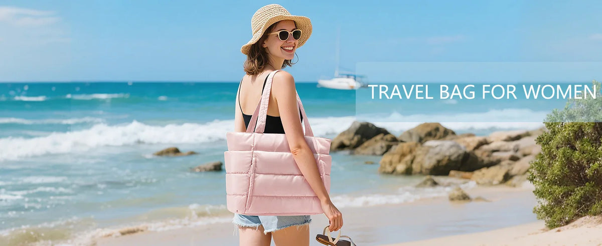 A woman wearing sunglasses and a straw hat stands by the ocean with a pink quilted travel bag.