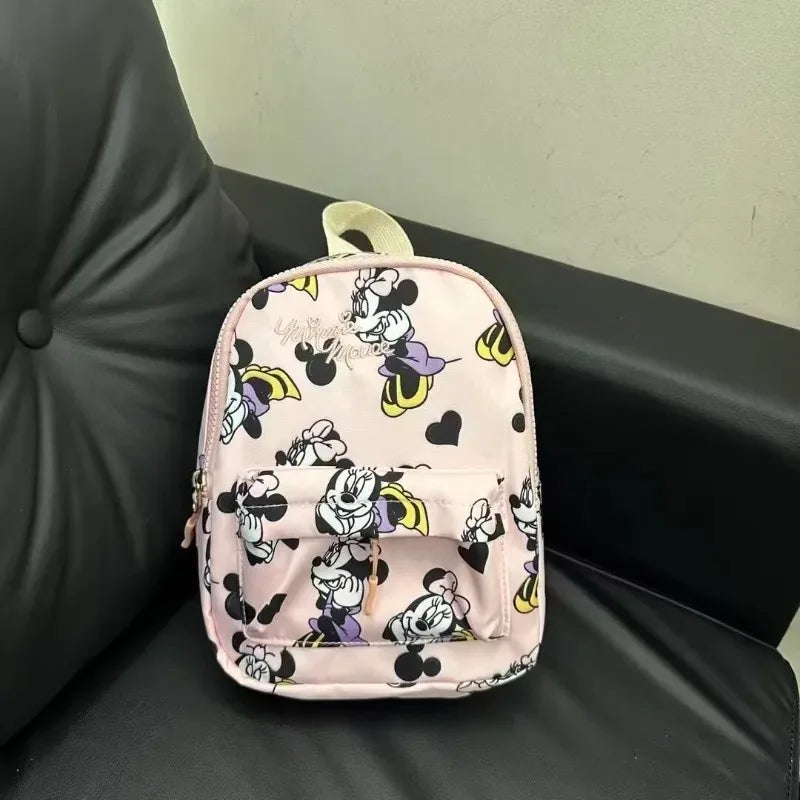 A pink and white Minnie Mouse themed fashion backpack resting on a black leather surface.