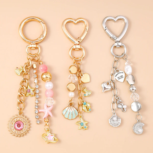 Gold and silver jewelry featuring a seashell starfish charm with pearl accents on a chain.