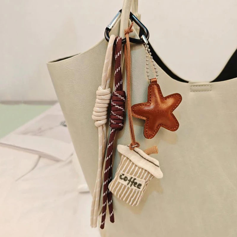 Colgante de cuero marrón con bordado de temática de café, colgando de una bolsa de tela beige.