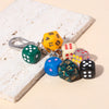 A set of colorful dice charms with numbers 1 to 6 are displayed on a white textured surface.