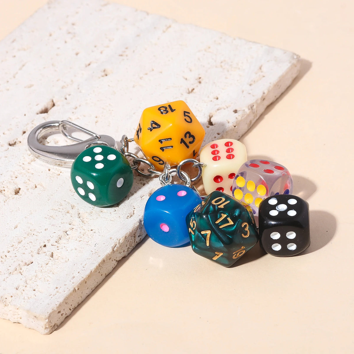 A set of colorful dice charms with numbers 1 to 6 are displayed on a white textured surface.