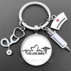 Silver keychain featuring a stethoscope charm and a medical syringe design on a circular pendant