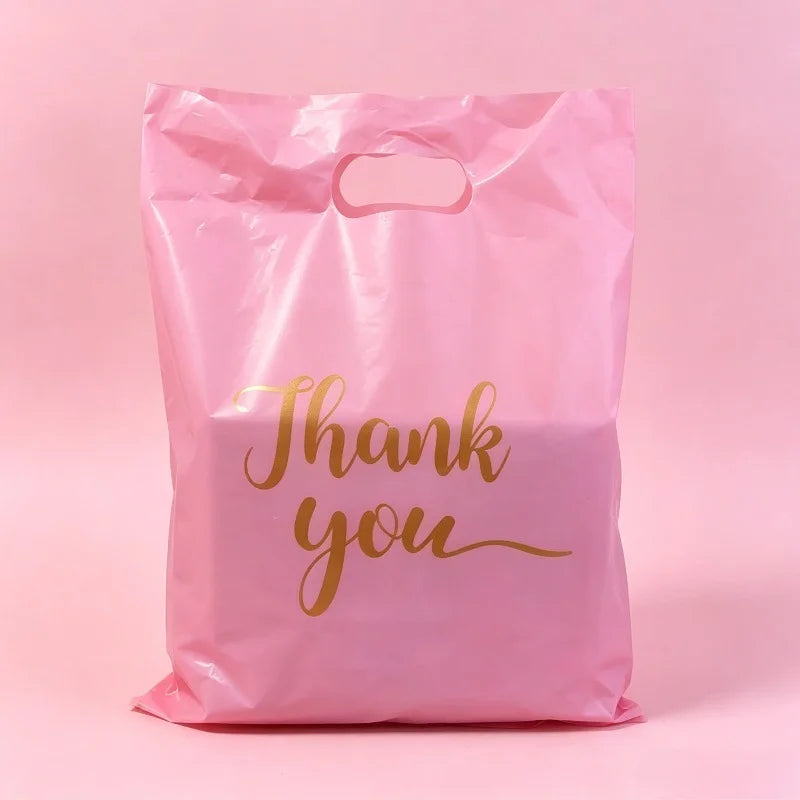 A pink bulk thank you gift bag with gold script text that reads Thank you