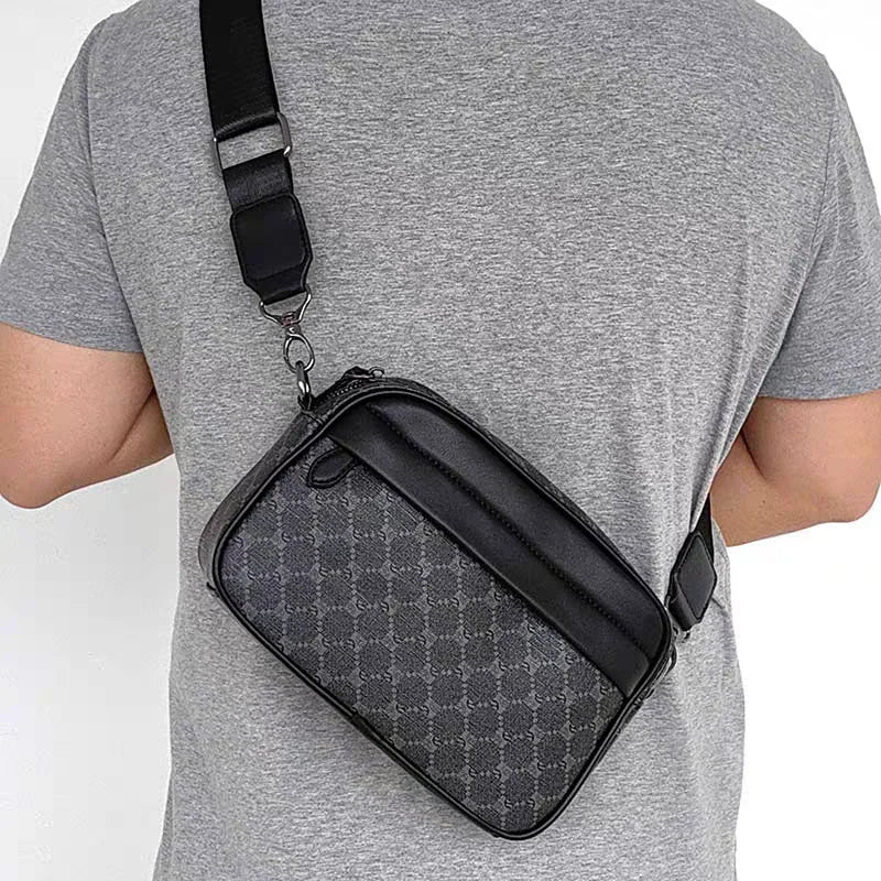 A black PU leather shoulder clutch bag with a strap is worn on a gray t-shirt.