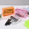 A set of transparent PVC travel makeup bags in orange and pink colors with various cosmetic items inside.