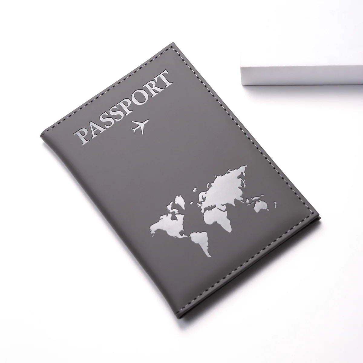 A gray leather passport wallet with a world map design and a small airplane icon.