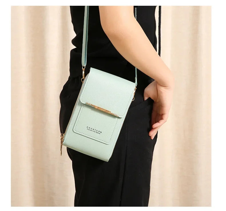 A light mint green luxury women's crossbody shoulder bag is shown being held by a person wearing black clothing.