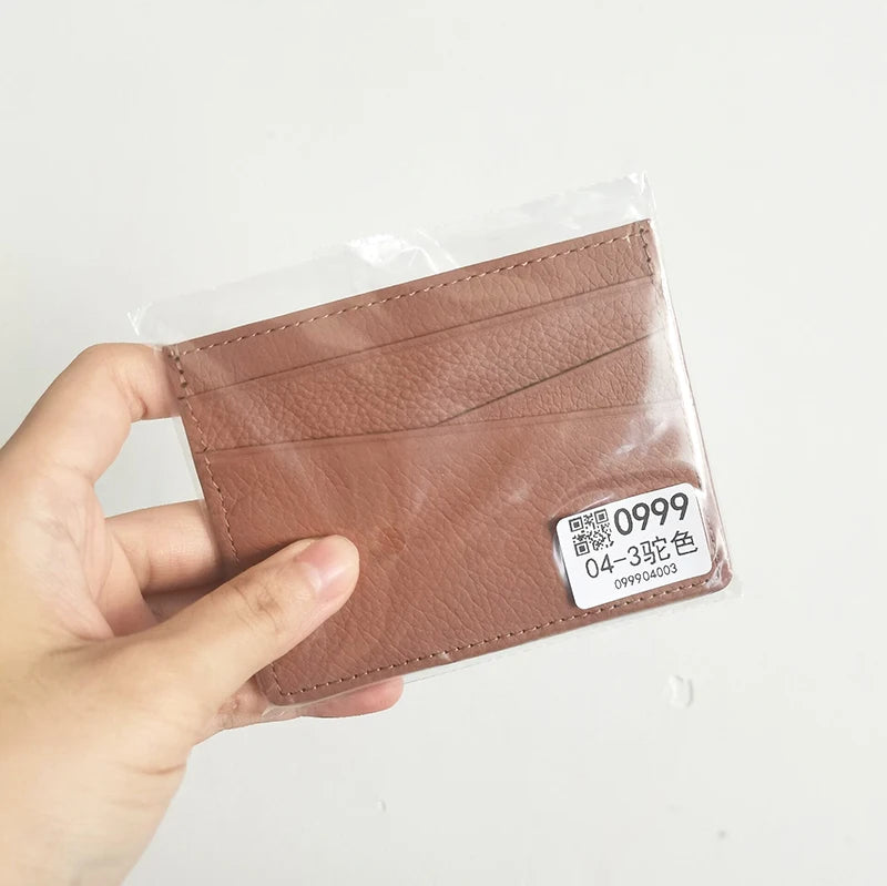 Une main tient un porte-cartes en cuir brun authentique avec un code QR gravé et une petite étiquette.